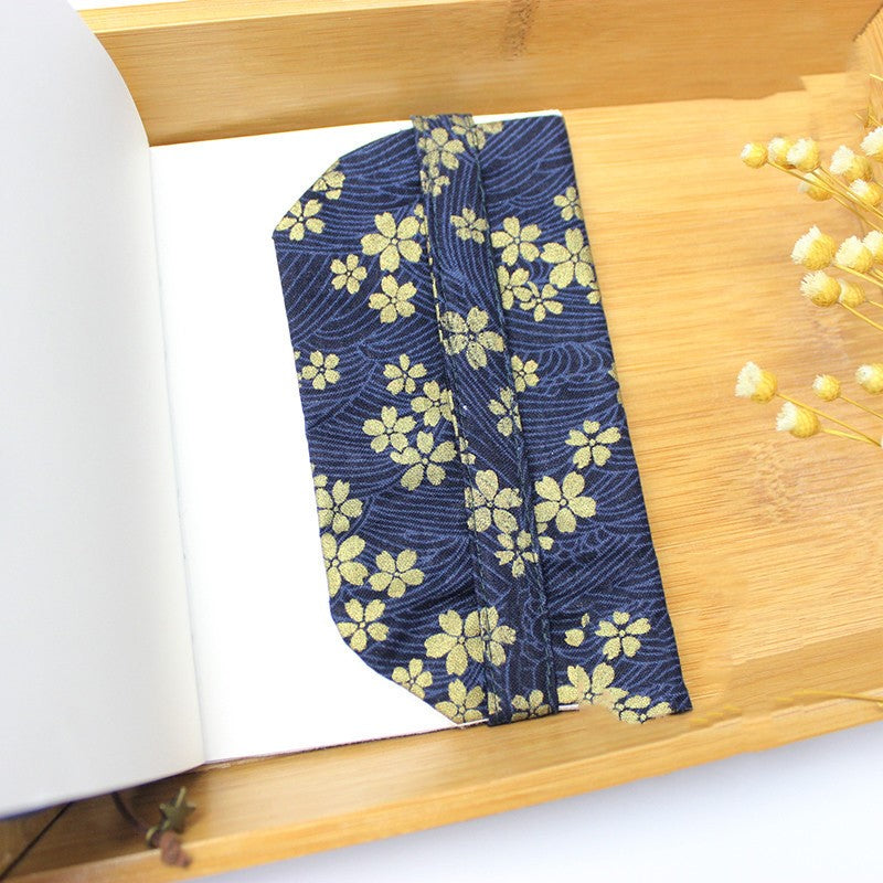Inside flap of the navy cherry blossom fabric book cover on an open book, with dried flowers