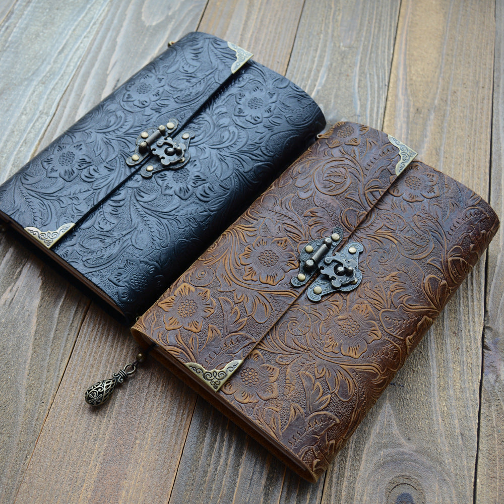 Black and brown embossed leather journals side by side on a wooden table