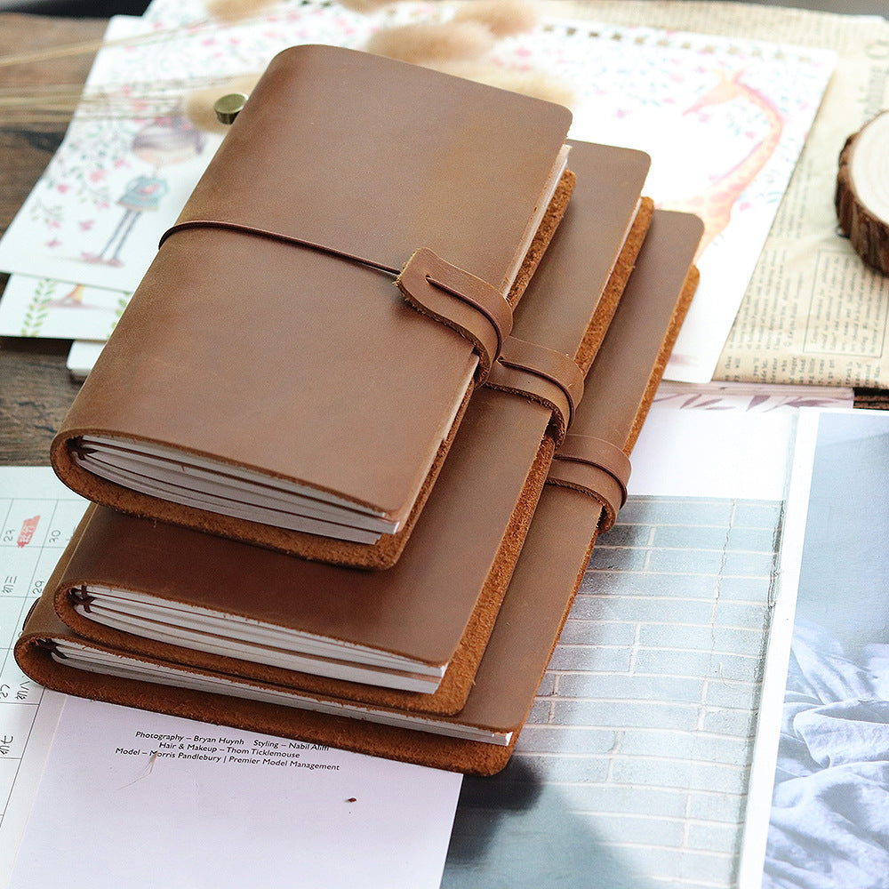 Light brown leather journals in several sizes on a desk with papers