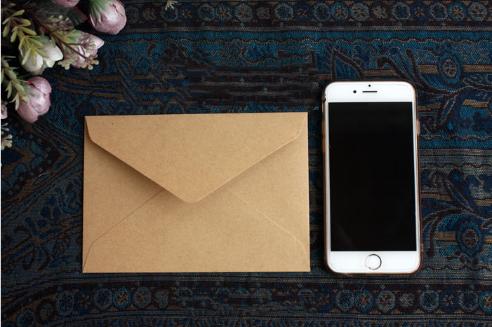 One kraft-brown envelope beside a phone for size comparison; the phone is not included