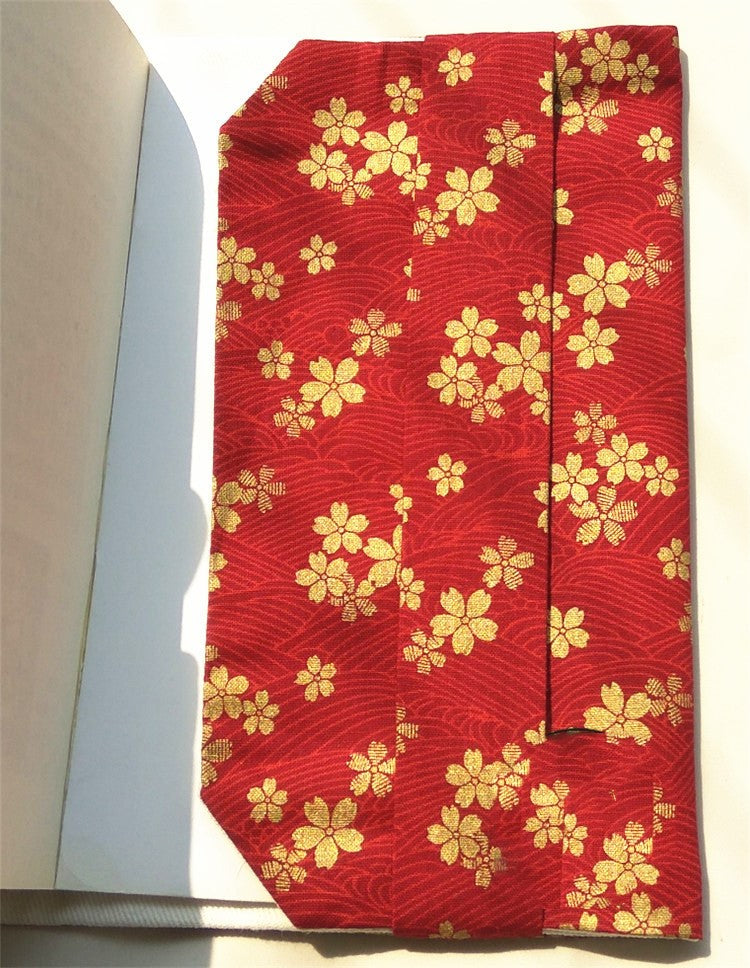 Inside flap of the red cherry blossom fabric book cover shown on an open book