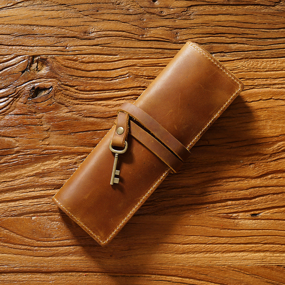 Brown leather pen roll wrapped with its strap and a metal key charm