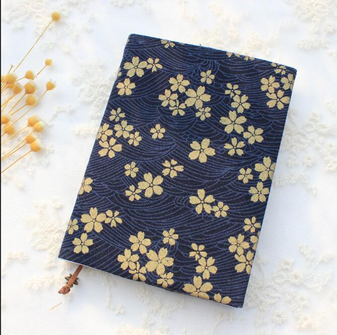 Navy blue A5 fabric book cover with a gold-tone cherry blossom and wave print, included in the book lover gift set